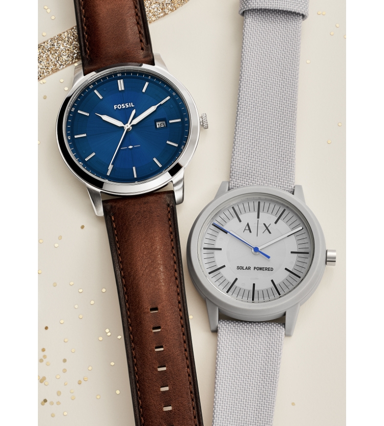 A Fossil and an Armani Exchange solar watch on top of gift packaging.